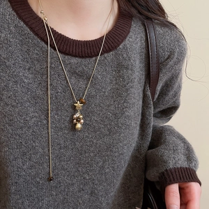 Gros plan d'un pendentif étoile dorée et pompon perlé sur collier en Y porté par un mannequin