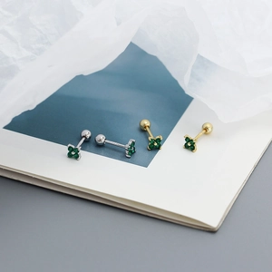 Detailed macro view of gold and silver four-leaf clover ear studs with green zircons