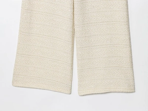 Gros plan détaillé sur le tissu en maille texturée blanc cassé de l'ourlet du pantalon