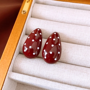 Detail of red teardrop earrings with white polka dots in a velvet jewelry box