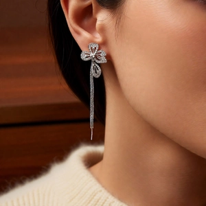 Close-up of floral silver tassel earrings with zircons worn by a model in soft light