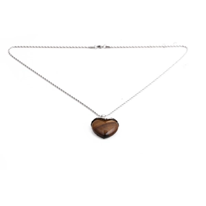 Macro detail of a heart-shaped tiger eye gemstone pendant on a silver rope chain necklace