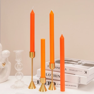 Set of four orange taper candles with three golden metal candle holders for home decor