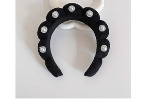 Detailed view of a black velvet headband with braided design and pearl embellishments