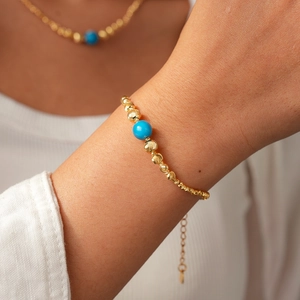 Close-up of 18K gold-plated beaded bracelet with blue stone bead and adjustable chain