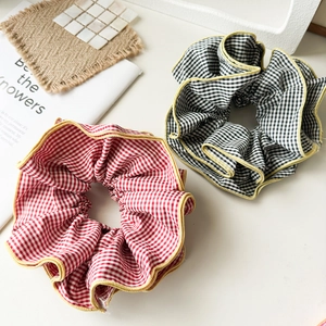 Detail of red and black oversized plaid scrunchies with yellow ruffled edges on a table