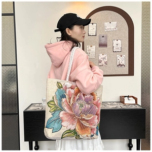 Close-up of vibrant peony floral embroidery on canvas tote bag with woven rope handle