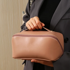 Pink PU leather makeup bag with large opening and handle shown by a model