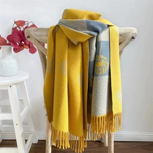 Detail of soft yellow and gray floral cashmere scarf with elegant fringe on wooden chair