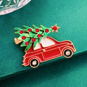 Detail of red Christmas car brooch with tree and rhinestones on dark green background