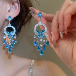Detail of blue teardrop and bow earrings with zircon stones on silver-tone metal
