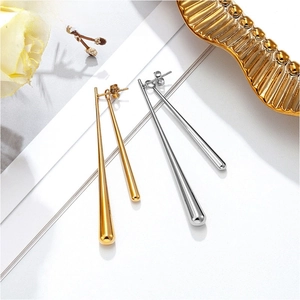 Polished gold and silver teardrop earrings on a white board with floral accents