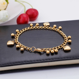 Detailed shot of golden stainless steel heart charm bracelet on a premium black texture