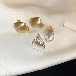 Boucles d'oreilles créoles carrées en or et argent brossé sur fond de soie élégante