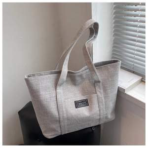 Close-up of gray fabric tote bag with Fashion label detail on a leather seat