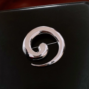 Detailed view of a silver polished spiral brooch with a secure needle pin structure