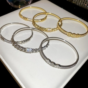 Detail of 18K gold and silver plated bangles with zircons on white leather