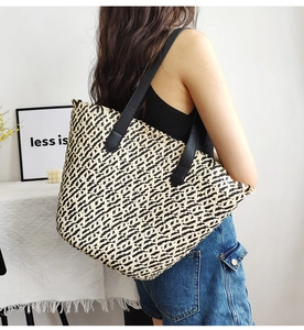 Close-up of a large woven tote bag with a two-tone zigzag pattern and long shoulder straps