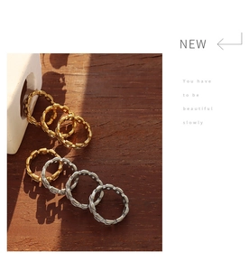 Detail of chunky gold and silver chain link rings on dark wood and stone background