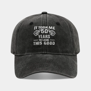 Close-up of white 50th birthday embroidery on a vintage washed black cotton baseball cap