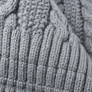 Primer plano de un gorro gris de punto trenzado con canalé vertical y textura suave