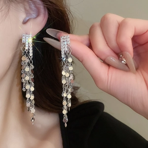Close-up of long silver tassel earrings with zircons and sequins on a female model
