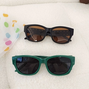 Kids vintage square sunglasses in black and green with UV protection on plush background