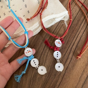 Handcrafted snowman fringe necklaces in blue and red velvet cord styles on wood background