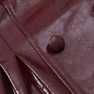 Dettaglio macro di ecopelle rosso scuro lucida con bottone e trama stropicciata