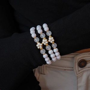 Detailed view of a three-piece acrylic beaded bracelet set with white flower charms on a wrist