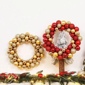 Festive gold and red Christmas ball wreath with glitter and matte finishes on white wall