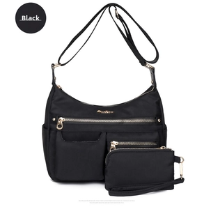 Close-up of black nylon shoulder bag with golden zippers and matching small pouch