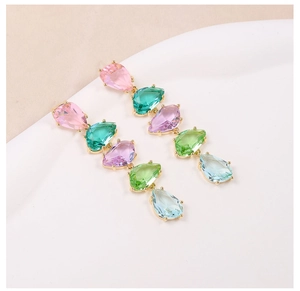 Detail of long drop earrings featuring colorful pear-shaped zircons in gold settings