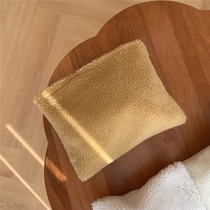 Close-up of khaki faux shearling makeup bag texture on a wooden table with soft sunlight