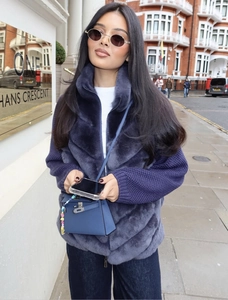 Détail de la veste en fausse fourrure violette avec manches en tricot et zip métallique