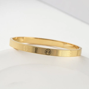 Detail of gold titanium steel bracelet with Saint Benedict medal and geometric patterns