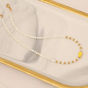 Close-up of pearl bead necklace with a small yellow fish pendant and gold clasp
