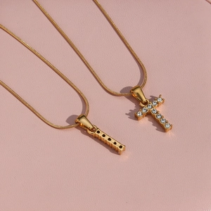 Detail of 18K gold plated snake chain with zircon cross pendant on pink leather