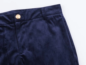 Detail of navy blue velvet trousers with elegant gold engraved buttons and waist design