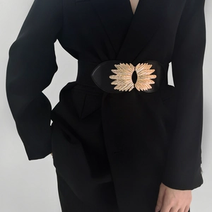 Close-up of women black elastic waist belt with gold leaf metal buckle on blazer