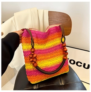 Detail of a rainbow gradient straw bag with dark brown round wooden bead handles