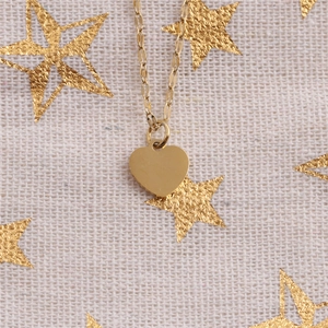 Close-up of golden titanium steel heart pendant necklace on star pattern fabric