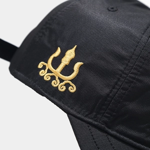 Dettaglio del ricamo in filo dorato sul tessuto di un cappello da baseball nero