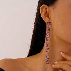 Detail shot of long tassel earrings with purple crystals and geometric hollow patterns