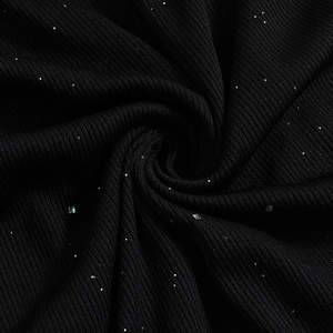 Macro texture of black ribbed knit fabric with sparkling sequins and elegant drape detail