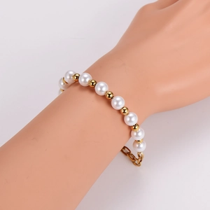 Minimalist pearl and gold bead stainless steel bracelet on model hand with adjustable clasp