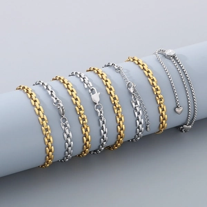 Detailed close-up of gold and silver polished metal watchband bracelets on a grey stand