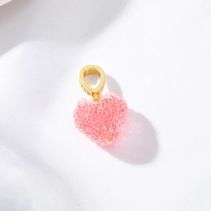 Detail view of pink textured heart pendant with a gold diamond-encrusted bail for jewelry