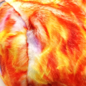 Macro detail of colorful tie-dye faux fur fabric showing soft plush texture and vibrant hues
