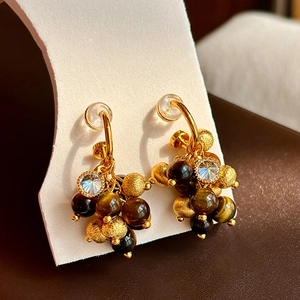 Elegant gold earrings with tiger eye beads and zircon charms on white display card